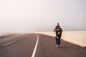 Image of a female hiker walking along an asphalt road .