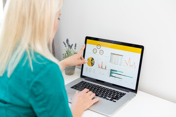 businesswoman analyzing statistics on laptop screen, working with financial graphs charts online, using business software for data analysis and project management concept, rear close up view