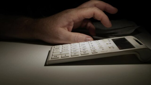 Businessman Working Late, with Invoices, Makes Nervous Gestures near Adding Machine. Accounting Fee and Taxes Calculations.