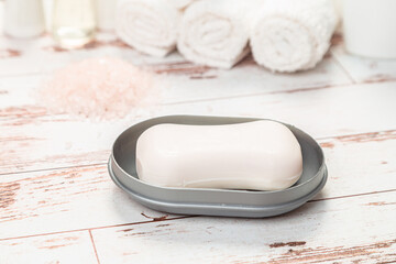 soap on a gray plastic soap dish, on a white wooden table.