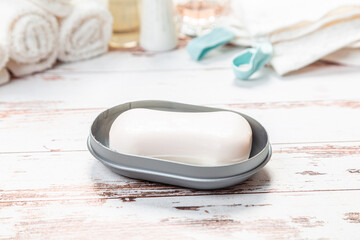 soap on a gray plastic soap dish, on a white wooden table.