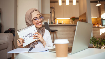 Muslim woman at home during pandemic isolation teaching students. Woman learning and teaching homeschooling in video conference. 