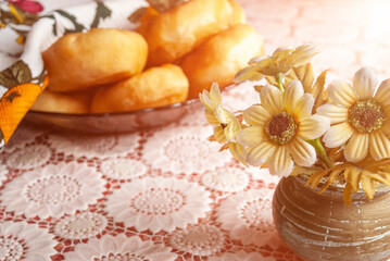Still life. Morning breakfast. Donuts on a macramé tablecloth and a vase of flowers.