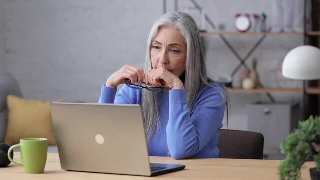 Depressed mature woman overworked on laptop computer. Tired worker recieved bad online news about dismissal from work. Financial crisis, burnout syndrome, overworking, depression, apathy.