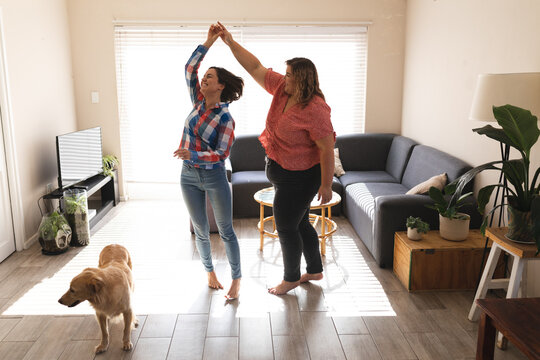 Happy lesbian couple dancing and smiling in living room
