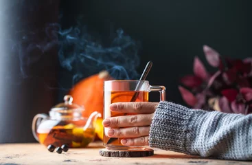 Poster A woman in a sweater holds a mug of hot tea with lemon. Autumn time.  © Виктория Попова