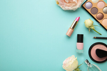 Obraz na płótnie Canvas Set of decorative cosmetics with flowers on blue background.