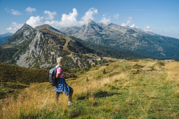 Woman with backpack enjoying view over Passo Rolle, - Italy , Dolomites. Scenery from summer...