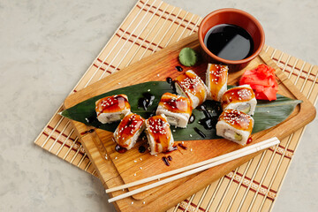 rolls with fish and filling served with soy sauce on a board