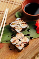 rolls with fish and filling served with soy sauce on a board