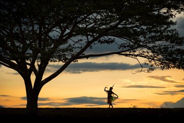 A shadow of a Thai dancer's dress standing near a big tree. traditional costume Ancient for a...