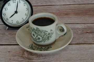 a cup of black coffee with alarm clock