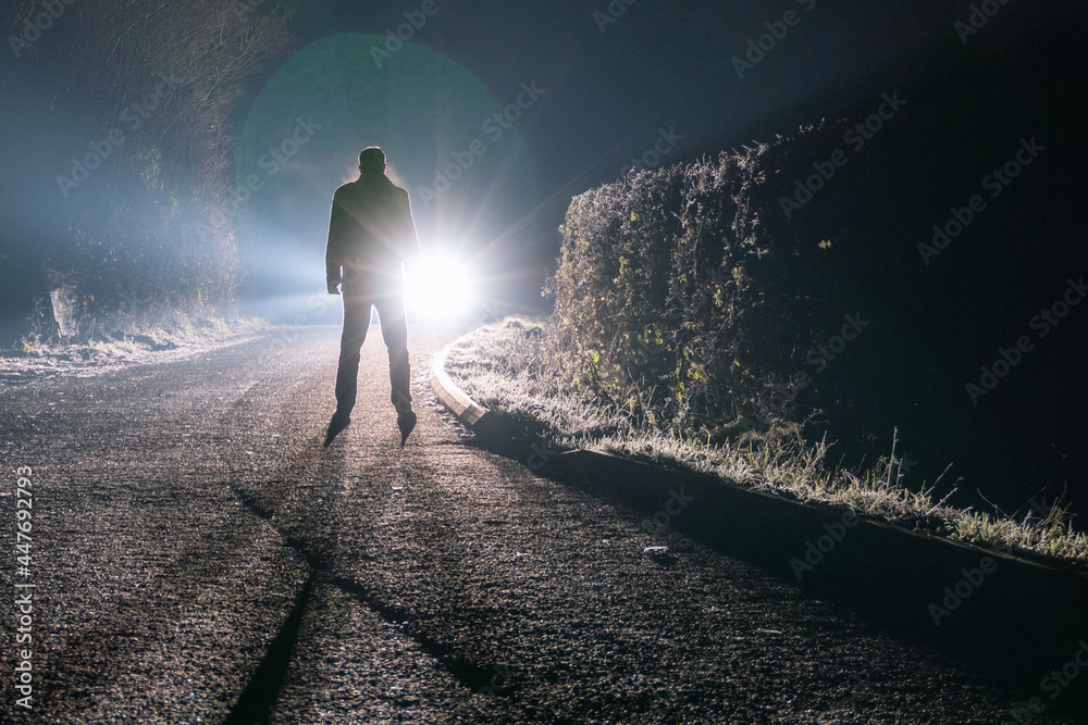 Poster a sinister male figure standing in front of a car. on a spooky country road on a foggy night.