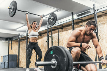 couple of man and woman doing weights in gym, crossfit