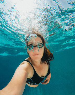 Underwater image of woman blowing swimming in a pool.