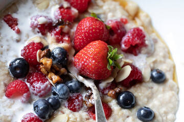 FRESH FRUIT PORRIDGE CLOSE UP ROASTED WALNUTS FLAKED ALMONDS MAPLE SYRUP VEGAN OAT CREAM  SPOON 