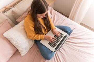 girl sitting on bed with laptop