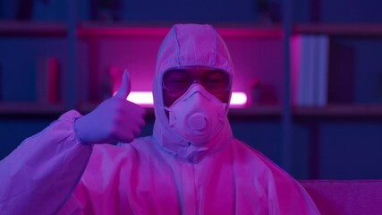 Black Man Wearing Hazmat Suit And Respirator Gesturing Thumbs-Up Indoors