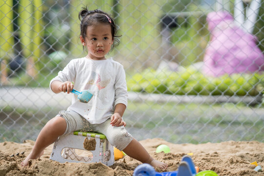 Southeast Asian Female Kid Playing With Sand At The Playground