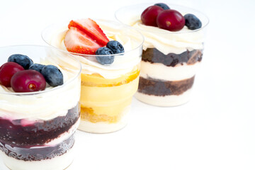 Thee portions of sweet cakes decorated with fresh berries in a row on white background