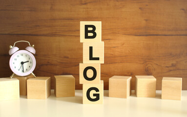 Four wooden cubes stacked vertically on a brown background form the word BLOG.