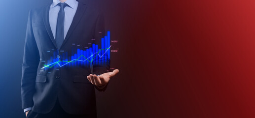 Business man holding holographic graphs and stock market statistics gain profits. Concept of growth planning and business strategy. Display of good economy form digital screen.