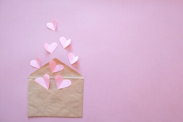 Creative minimal Valentine's Day concept. Envelope, valentines, white and pink heart confetti on a pastel pink background. Flat lay, top view, copy space
