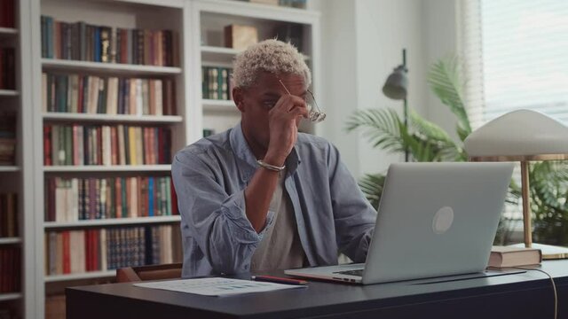 Upset young African American business man covers his face with palms in frustration sitting at laptop getting bad news looks very disappointed lost document problems with device. Too much work concept