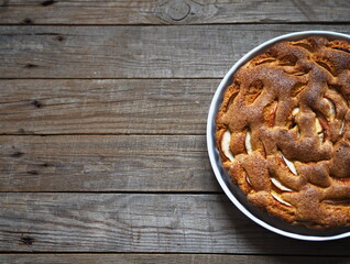 Round apple pie or sponge cake on wooden rustic table. Home cooking.