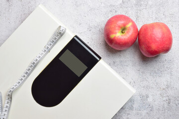 Concept of health, maintaining proper weight and good nutrition. Digital scale and two apples, along with a tape measure.