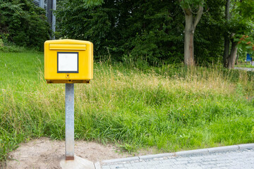 a yellow postbox stands on the outskirts of the road