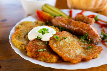 potato pancakes with fried sausages on a white plate