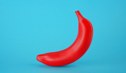 Red banana on a blue background. Cheating concept and fake news