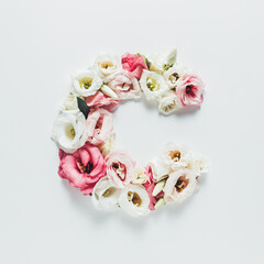 Letter C made with flower and leaves on bright white background. Floral mother's day alphabet concept. Spring blossom, valentine or romantic font collection. Flat lay, top view.