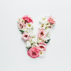 Obraz na płótnie Canvas Letter V made with flower and leaves on bright white background. Floral mother's day alphabet concept. Spring blossom, valentine or romantic font collection. Flat lay, top view.