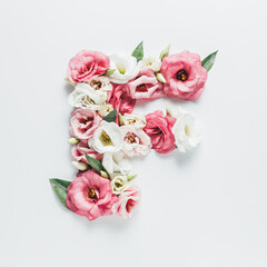 Letter F made with flower and leaves on bright white background. Floral mother's day alphabet concept. Spring blossom, valentine or romantic font collection. Flat lay, top view.