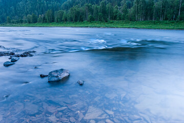 Landscapes of Siberia. Evening landscape at sunset. Mountains, forest, river and water at long exposure. Kemerovo region. Russia