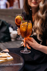 Women making a celebratory toast with aperol spritz cocktails at summer party