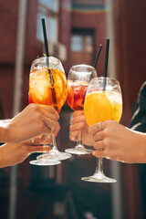 Friends toasting, saying cheers holding tropical cocktails. Making celebratory toast 