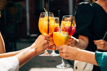 Friends making a celebratory toast with summer cocktails. Party with alcoholic drinks - obrazy, fototapety, plakaty