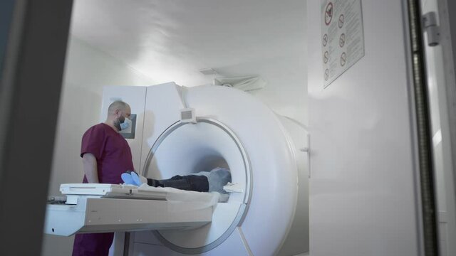 The doctor conducts an MRI or PET scan of a patient in a modern clinic. Girl on the bed inside a 3D scan machine. Magnetic resonance imaging in the study of the human body. The woman is doing CT scan