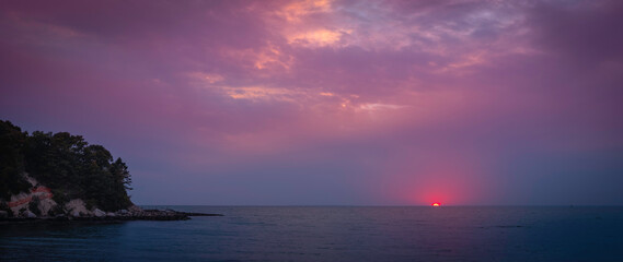 Moody pink and purple sunset seascape over Old Silver Beach in Falmouth on Cape Cod