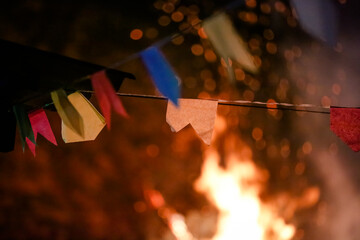 Bandeirinha de festa sobre fogueira de fundo com cores lindas.