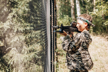 Boy looking into the optical sight a weapon. Children playing laser tag shooting game in outdoor....