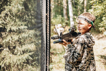 Boy with a weapon in his hand playing laser tag shooting game in outdoor. War simulation game