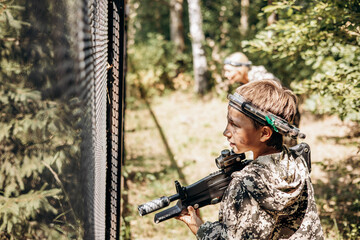 Boy with a weapon in his hand playing laser tag shooting game in outdoor. War simulation game