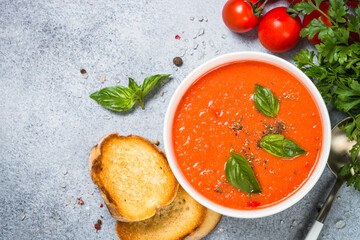 Tomato soup with basil. Summer cold vegan dish. Top view at stone background.