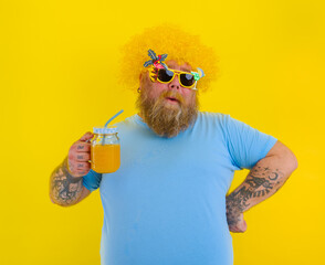 Fat happy man with wig in head and sunglasses drinks a fruit juice