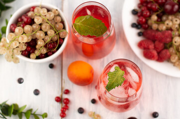 On a gray background, a blurred image of fruit drinks with ice cubes and fruits in a bowl. View from above.