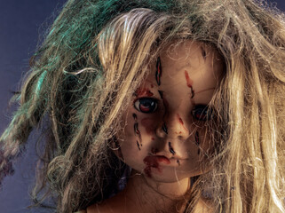 The doll's scratched face is covered with blood. A symbol of defenseless child violence.